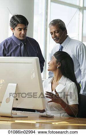 Indian business people talking to each other around a computer View Large Photo Image Picture - Indian business people talking to each other around a computer. Fotosearch