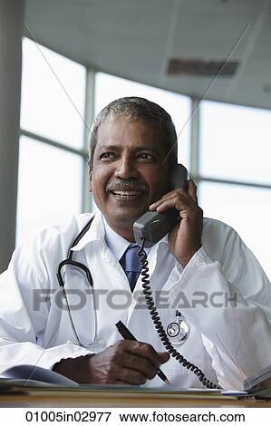Indian doctor talking on phone and smiling View Large Photo Image Stock Photo - Indian doctor talking on phone and smiling. Fotosearch