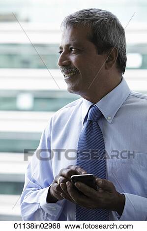 Profile of Indian man texting on phone View Large Photo Image Stock Photo - Profile of Indian man texting on phone. Fotosearch