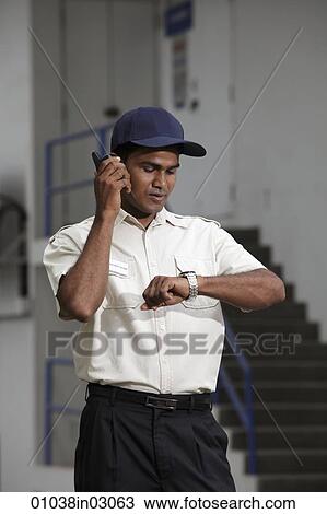 Security guard looking at watch and talking on phone View Large Photo Image Stock Image - Security guard looking at watch and talking on phone. Fotosearch