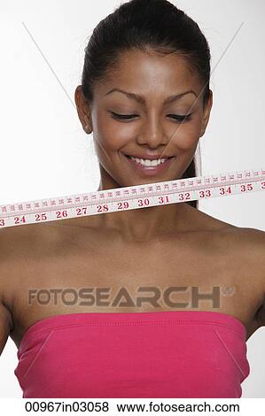 Woman looking at tape measure and smiling View Large Photo Image Stock Photo - Woman looking at tape measure and smiling. Fotosearch