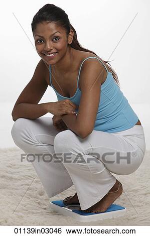 woman squatting on scale and smiling View Large Photo Image Stock Photograph - woman squatting on scale and smiling. Fotosearch