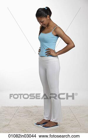 woman standing with hands on hips and looking at scale View Large Photo Image Picture - woman standing with hands on hips and looking at scale. Fotosearch