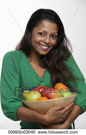 Woman wearing green top holding bowl of fruit View Large Photo Image Stock Image - Woman wearing green top holding bowl of fruit. Fotosearch
