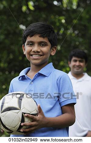 Young boy holding ball while father stands behind him View Large Photo Image Stock Photo - Young boy holding ball while father stands behind him. Fotosearch