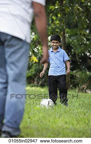 Stock Photo - Young boy kicking ball to his father. Fotosearch