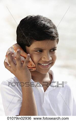 young boy listening to sea shell and smiling View Large Photo Image Stock Photograph - young boy listening to sea shell and smiling. Fotosearch