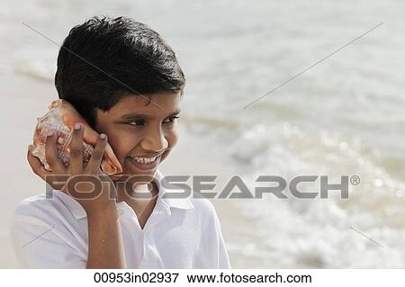 Young boy listening to sea shell View Large Photo Image Stock Photo - Young boy listening to sea shell. Fotosearch