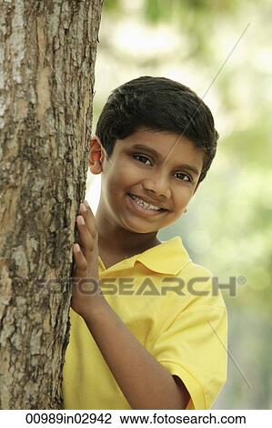 Young boy peeking out from behind a tree View Large Photo Image Stock Image - Young boy peeking out from behind a tree. Fotosearch