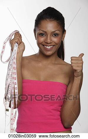 Young smiling woman holding tape measures and giving thumbs up View Large Photo Image Stock Photo - Young smiling woman holding tape measures and giving thumbs up. Fotosearch