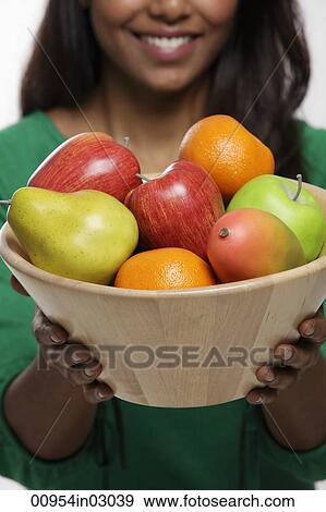 Young woman holding a bowl of fruit View Large Photo Image Stock Photo - Young woman holding a bowl of fruit. Fotosearch