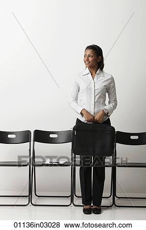 Stock Photo - Young woman holding briefcase and standing. Fotosearch
