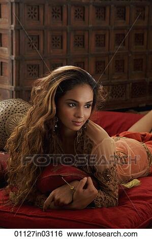young woman laying on stomach holding pillows View Large Photo Image Stock Photograph - young woman laying on stomach holding pillows. Fotosearch
