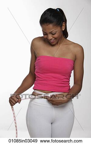 Young woman measuring herself with tape measure and smiling View Large Photo Image Stock Photo - Young woman measuring herself with tape measure and smiling. Fotosearch