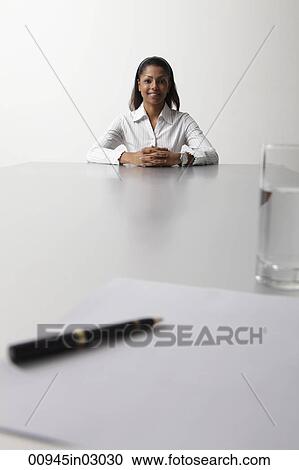 young woman sitting at end of the table being interviewed View Large Photo Image Stock Image - young woman sitting at end of the table being interviewed. Fotosearch