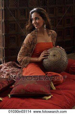 Young woman sitting on pillows holding Indian antiques View Large Photo Image Picture - Young woman sitting on pillows holding Indian antiques. Fotosearch