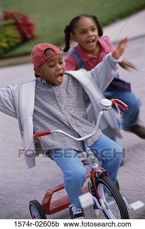 Boy and a girl playing on a tricycle View Large Photo Image Stock Image - Boy and a girl playing on a tricycle. Fotosearch
