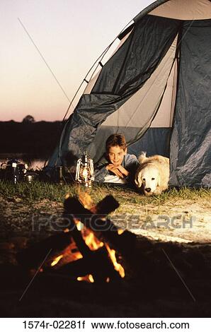 Stock Image - Boy camping in a tent with his dog. Fotosearch