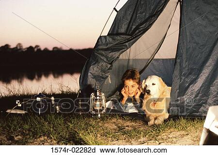 Stock Image - Boy camping in a tent with his dog. Fotosearch