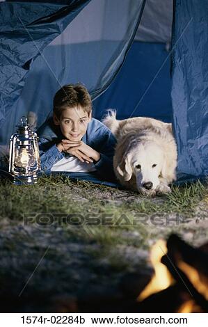 Stock Image - Boy camping in a tent with his dog. Fotosearch