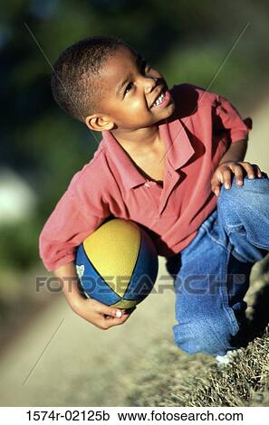 Boy kneeling with a rugby ball View Large Photo Image Stock Image - Boy kneeling with a rugby ball. Fotosearch
