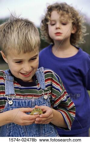 Stock Image - Boy standing with his friend holding a frog. Fotosearch