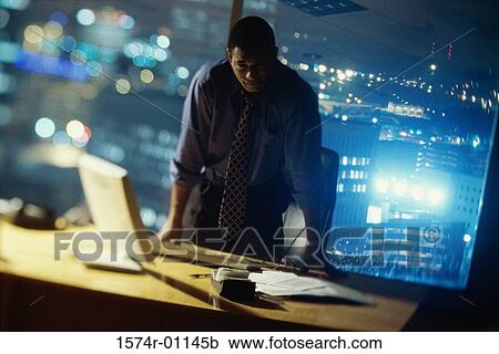 Stock Image - Businessman leaning against a desk. Fotosearch