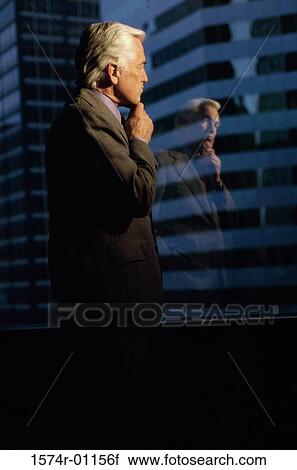 Stock Image - Businessman looking out of a window. Fotosearch