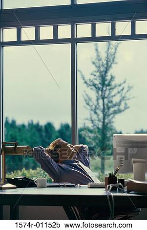 Businessman sitting in an office looking out of a window View Large Photo Image Stock Image - Businessman sitting in an office looking out of a window. Fotosearch