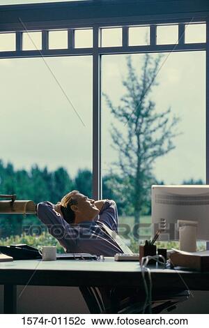 Businessman sitting in an office looking out of a window View Large Photo Image Stock Image - Businessman sitting in an office looking out of a window. Fotosearch