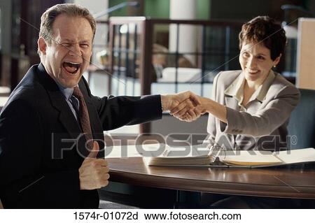 Stock Image - Businesswoman and a businessman shaking hands. Fotosearch
