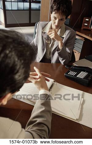 Stock Image - Businesswoman and a businessman discussing in an office. Fotosearch