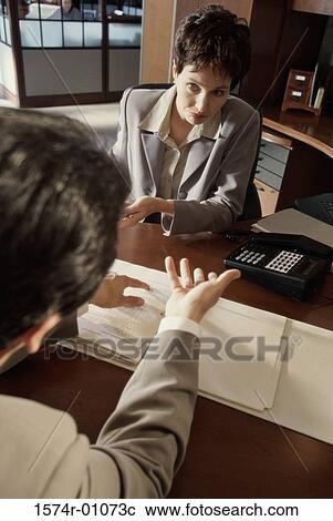 Stock Image - Businesswoman and a businessman discussing in an office. Fotosearch