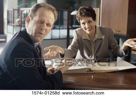 Stock Image - Businesswoman and a businessman discussing in an office. Fotosearch
