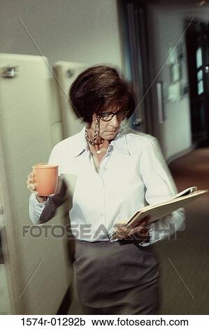 Stock Image - Businesswoman holding a cup of coffee and files. Fotosearch