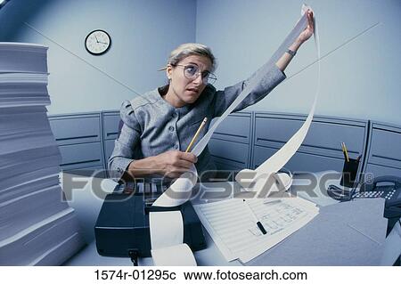 Stock Image - Businesswoman looking at an adding machine paper roll. Fotosearch