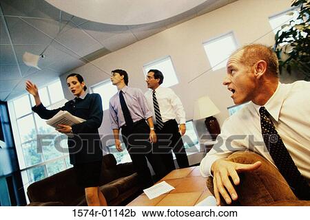 Stock Image - Businesswoman throwing documents with three businessmen watching. Fotosearch
