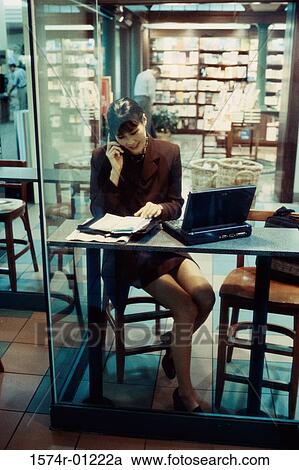 Stock Image - Businesswoman with a laptop talking on a mobile phone. Fotosearch