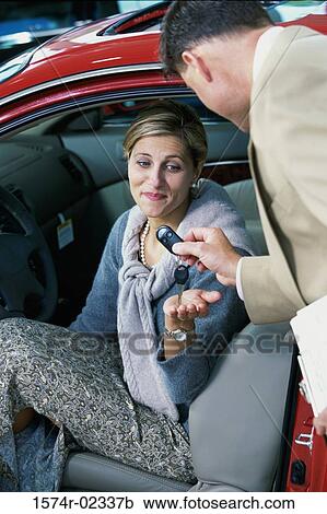 Car salesman giving the car keys to a mid adult woman View Large Photo Image Stock Image - Car salesman giving the car keys to a mid adult woman. Fotosearch
