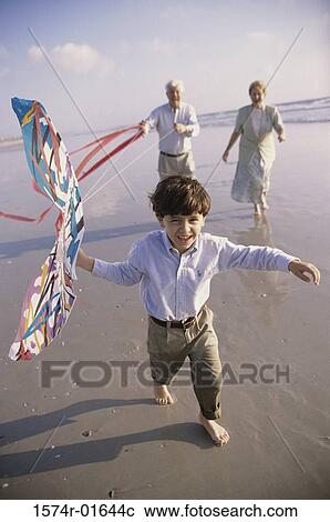 Child flying a kite at the beach with his grandparents View Large Photo Image Stock Image - Child flying a kite at the beach with his grandparents. Fotosearch