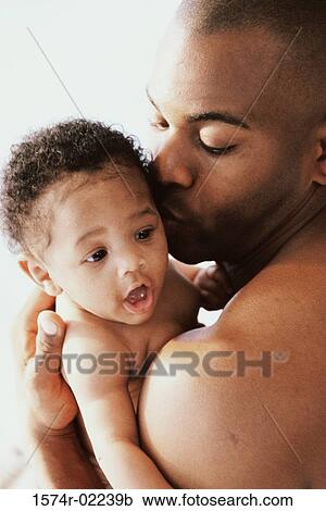 Stock Image - Close-up of a father kissing his baby boy. Fotosearch