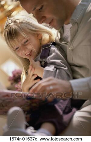 Stock Image - Close-up of a father reading to his daughter. Fotosearch