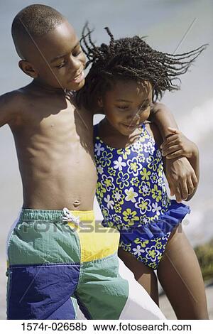 Stock Image - Close-up of a girl and a boy holding each other on the beach. Fotosearch