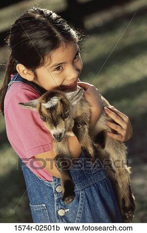 Stock Image - Close-up of a girl holding a kid goat in her arms. Fotosearch