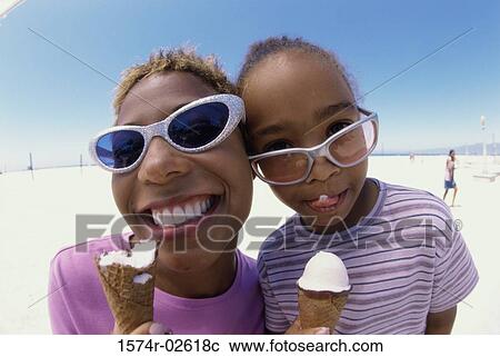 Stock Image - Close-up of a mother and her daughter holding ice cream cones. Fotosearch