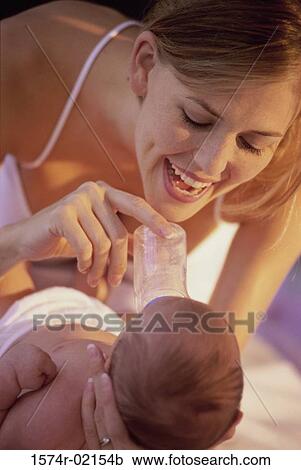 Stock Image - Close-up of a mother feeding her baby girl with a baby bottle. Fotosearch