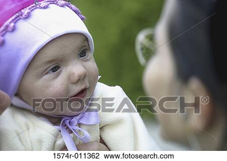 Close-up of a mother holding her baby girl smiling View Large Photo Image Stock Image - Close-up of a mother holding her baby girl smiling. Fotosearch