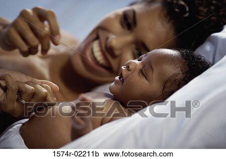 Stock Image - Close-up of a mother lying down with her baby boy. Fotosearch