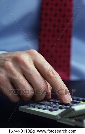 Stock Image - Close-up of a person's hand operating a calculator. Fotosearch