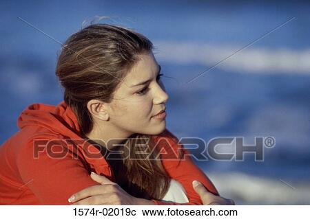 Stock Image - Close-up of a teenage girl sitting at the beach. Fotosearch